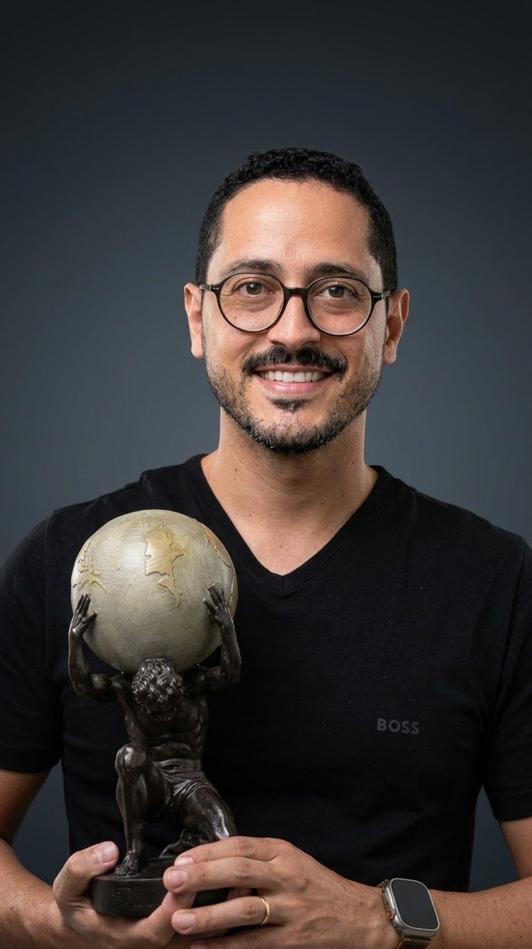 Wenderson Araújo segurando uma escultura de Atlas sustentando o globo